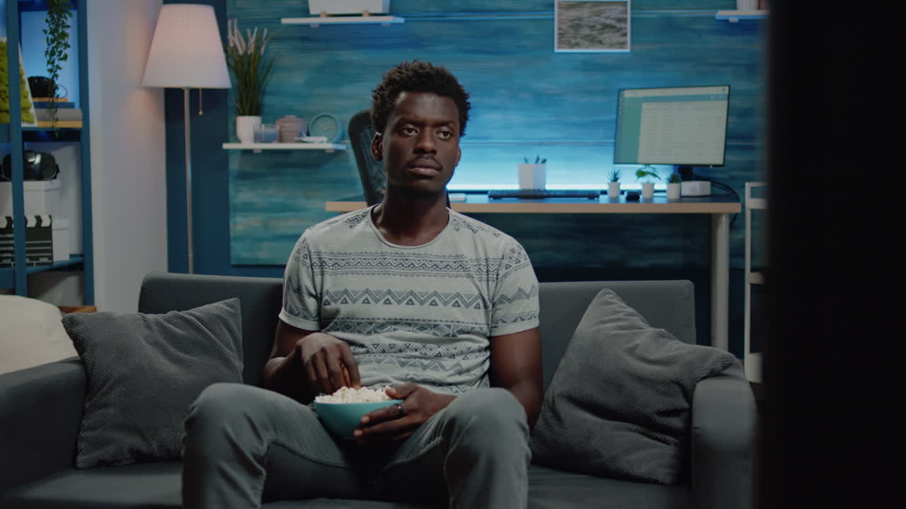 Adult looking at television screen and having snack