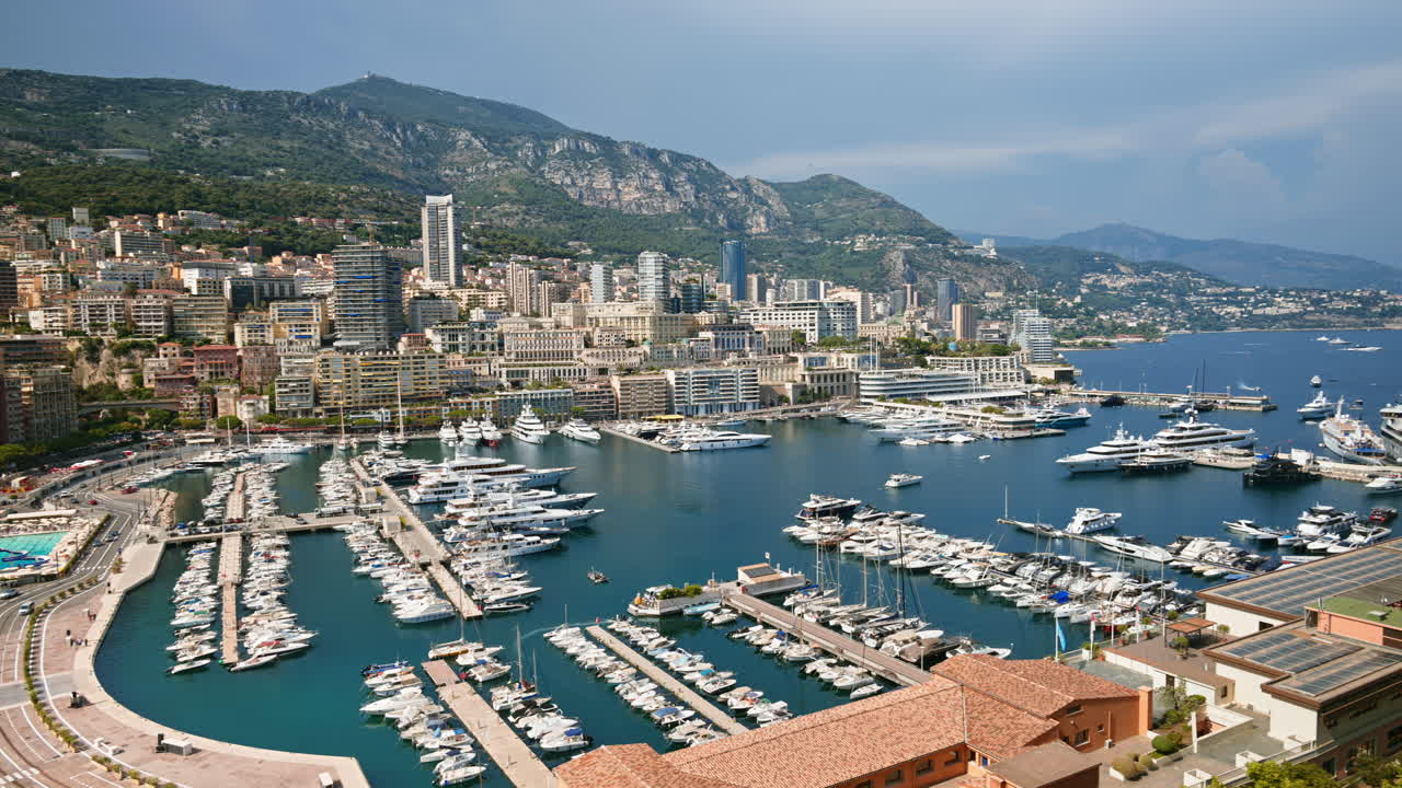 Vista aerea di barche bianche ormeggiate nel porto turistico di Monaco, con lo skyline sullo sfondo