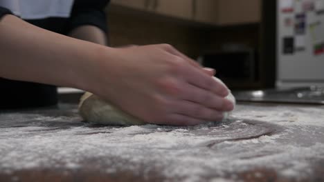 Female-hands-prepare-and-kneed-fresh-white-bread-dough-on-kitchen-bench-covered-with-flour-before-baking-at-home