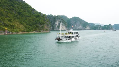 Ha-Long-Bay-Cruise:-Passing-Cruise-Boats-with-Rocky-Limestone-Mountains-on-a-Gloomy-Day