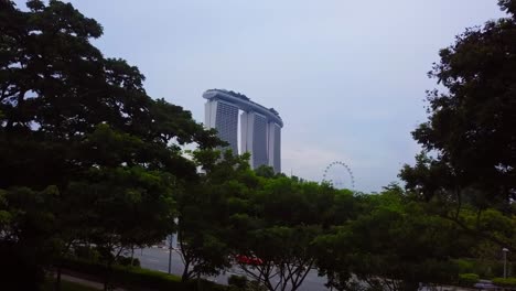 aerial drone shot rising up from trees, gradually revealing the marina bay sands hotel in singapore