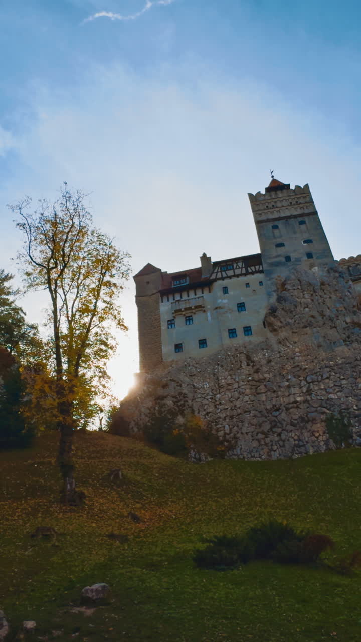 Famous Count Dracula castle on the hill among the colorful trees. Low angle view. Autumn in Romania. Vertical video