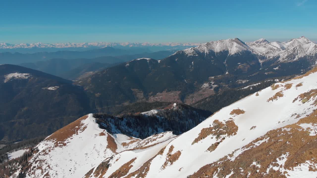Aerial drone shot of a ridge of the Lagorai mountains, revealing the village of Palù del Fersiona in val dei Mocheni in the distance and the Valcava valley