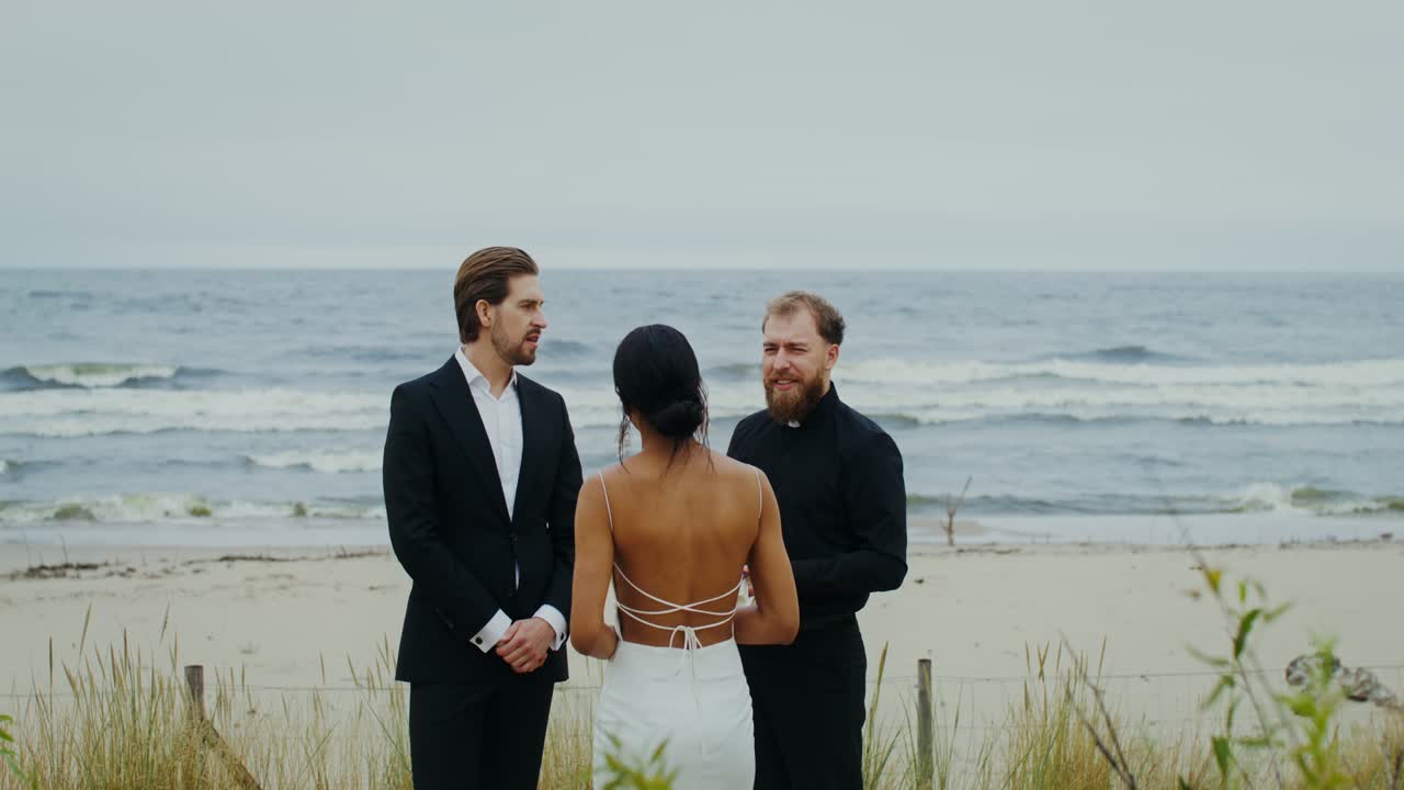 Cerimonia di matrimonio in spiaggia con sposa, sposo e sacerdote