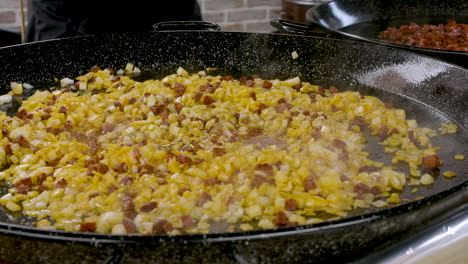 turning shot over the preparation of a paella pan showing the chorizo and onion frying in the pan