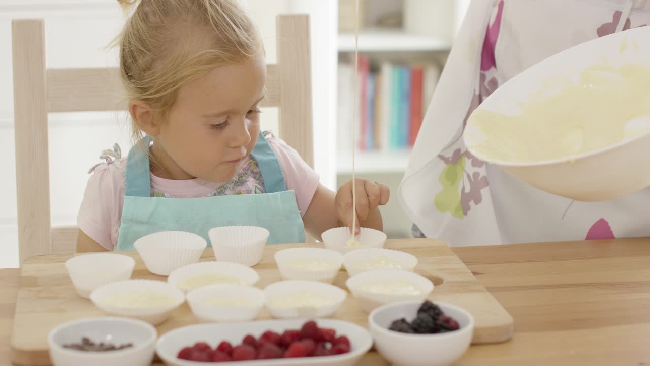 niña riendo con tazas de muffin y padre en delantal