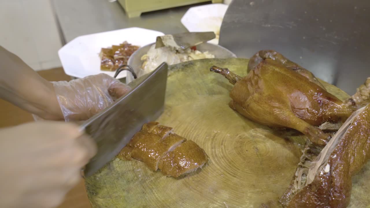 Man's Hands Chopping Roasted Goose With A Butcher's Knife In Guangzhou, China - close up