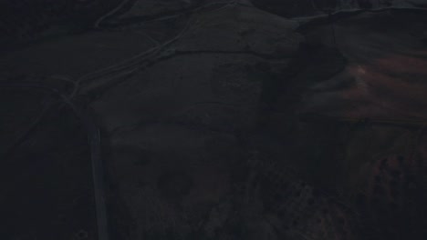 drone volando hacia atrás con la cámara inclinándose lentamente desde la posición hacia abajo sobre un paisaje italiano con colinas, árboles y campos de hierba al amanecer en 4k