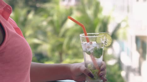 woman in pink blouse holds cold tasty beverage on terrace