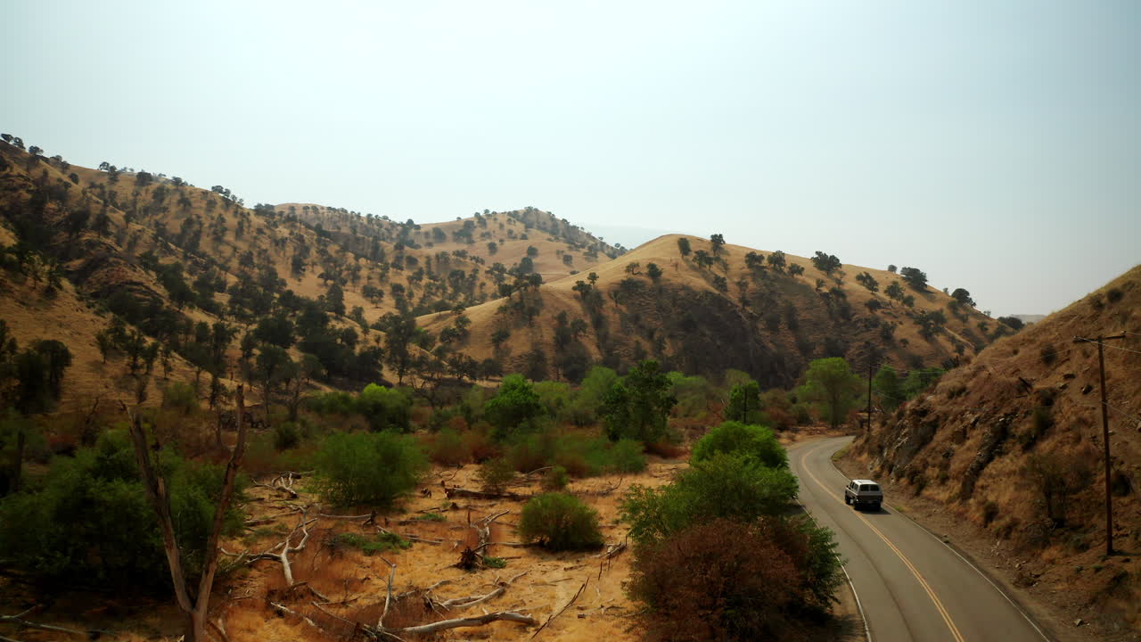 um carro solitário dirige ao longo de uma estrada sinuosa entre as colinas no deserto de mojave, no sul da califórnia - vista aérea