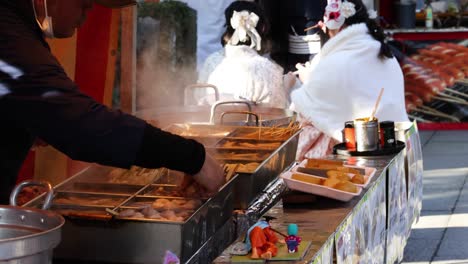 vendor cooking oden in steaming pots outdoors