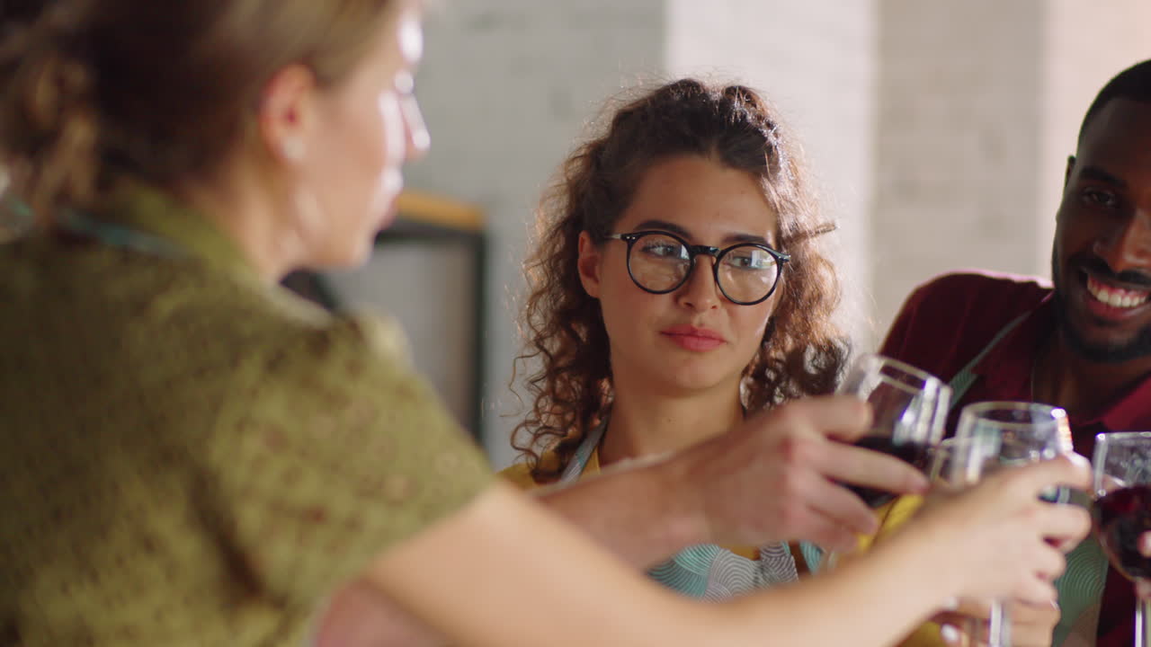 amigos multiétnicos bebiendo vino durante la clase de cocina
