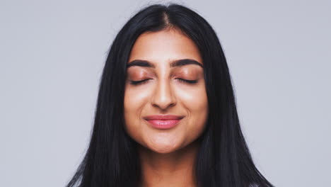 Head-And-Shoulders-Studio-Shot-Of-Calm-Woman-Smiling-At-Camera-In-Slow-Motion