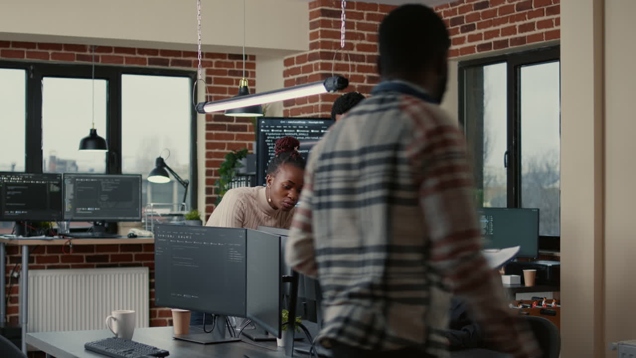 Software engineers brainstorming ideas looking at code on computer screens asking feedback