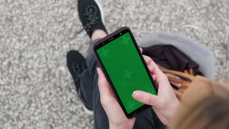 smartphone green screen mockup, top view of woman using phone.