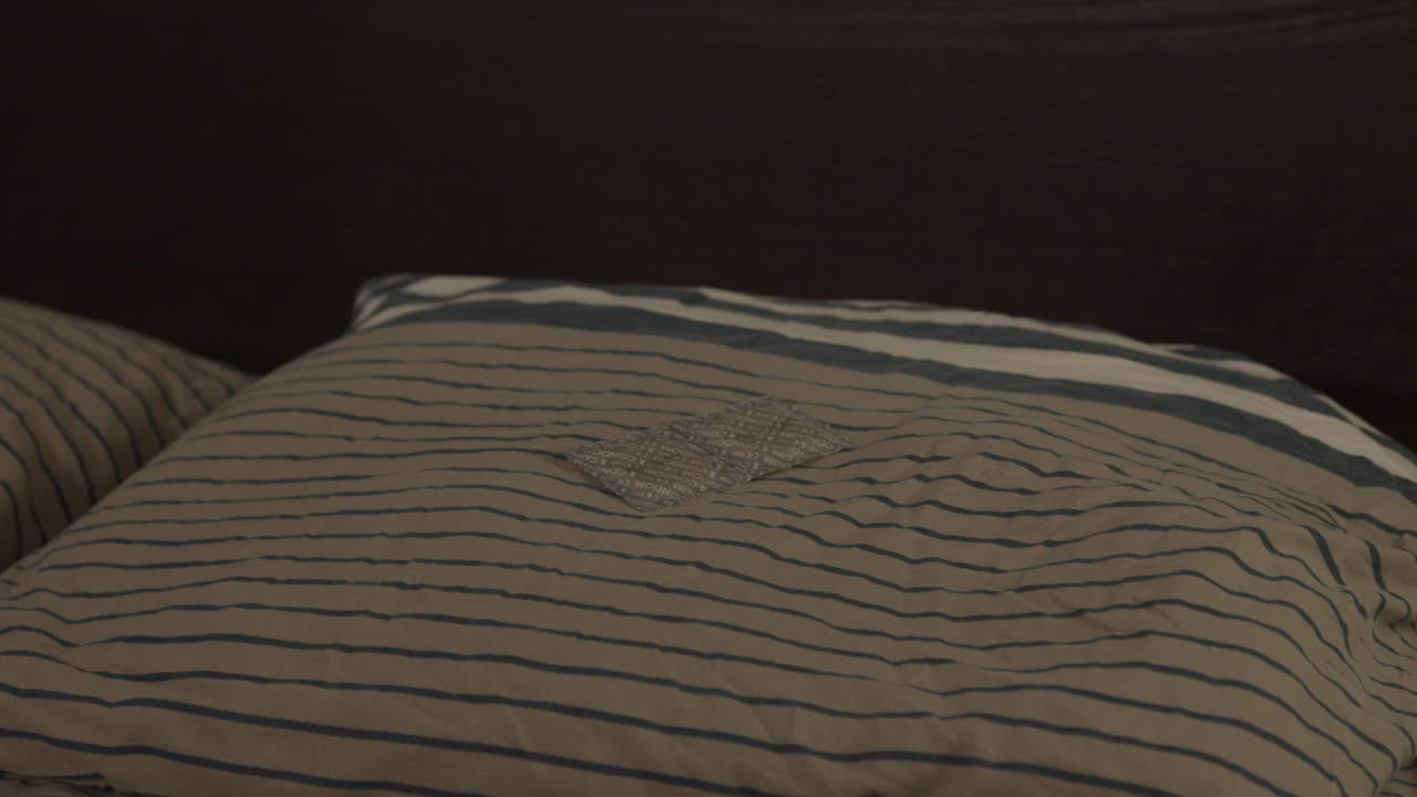 muñeca ancha de un par de condones envueltos sobre una almohada en la cama