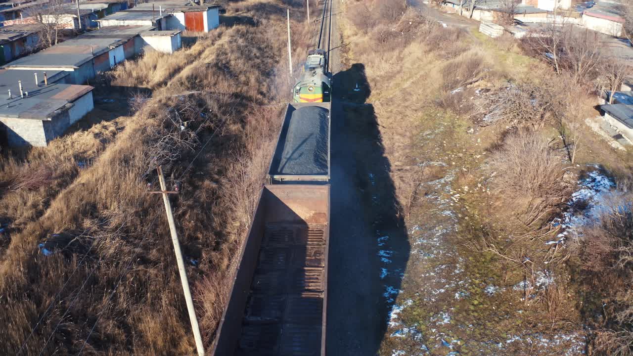 Freight train moving in winter. Top view on a cargo train on rails. Freight transport, railroad and transportation concept. Aerial view.