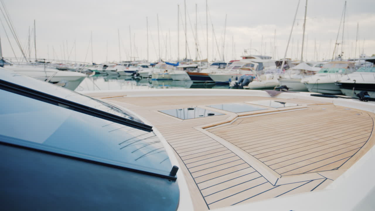 A luxury yacht deck overlooking a peaceful marina filled with sailboats and motor yachts under soft daylight