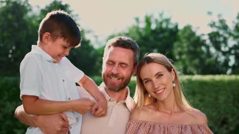 Happy-parents-and-son-smiling-at-camera.-Joyful-man-holding-boy-on-hands