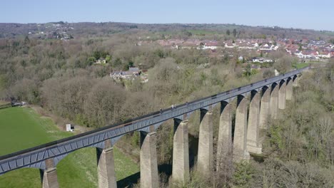 people walk across the beautiful narrow boat canal route called the pontcysyllte aqueduct famously designed by thomas telford, located in the beautiful welsh countryside, a huge bridge viaduct