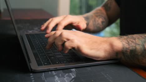primer plano de un hombre escribiendo en una computadora portátil.
