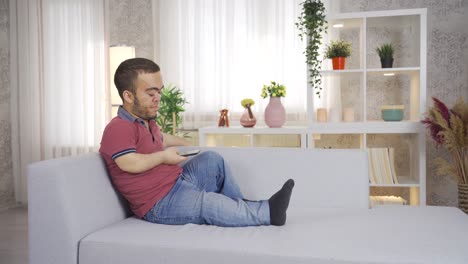 Young-dwarf-man-sitting-on-sofa-at-home-and-using-smartphone.