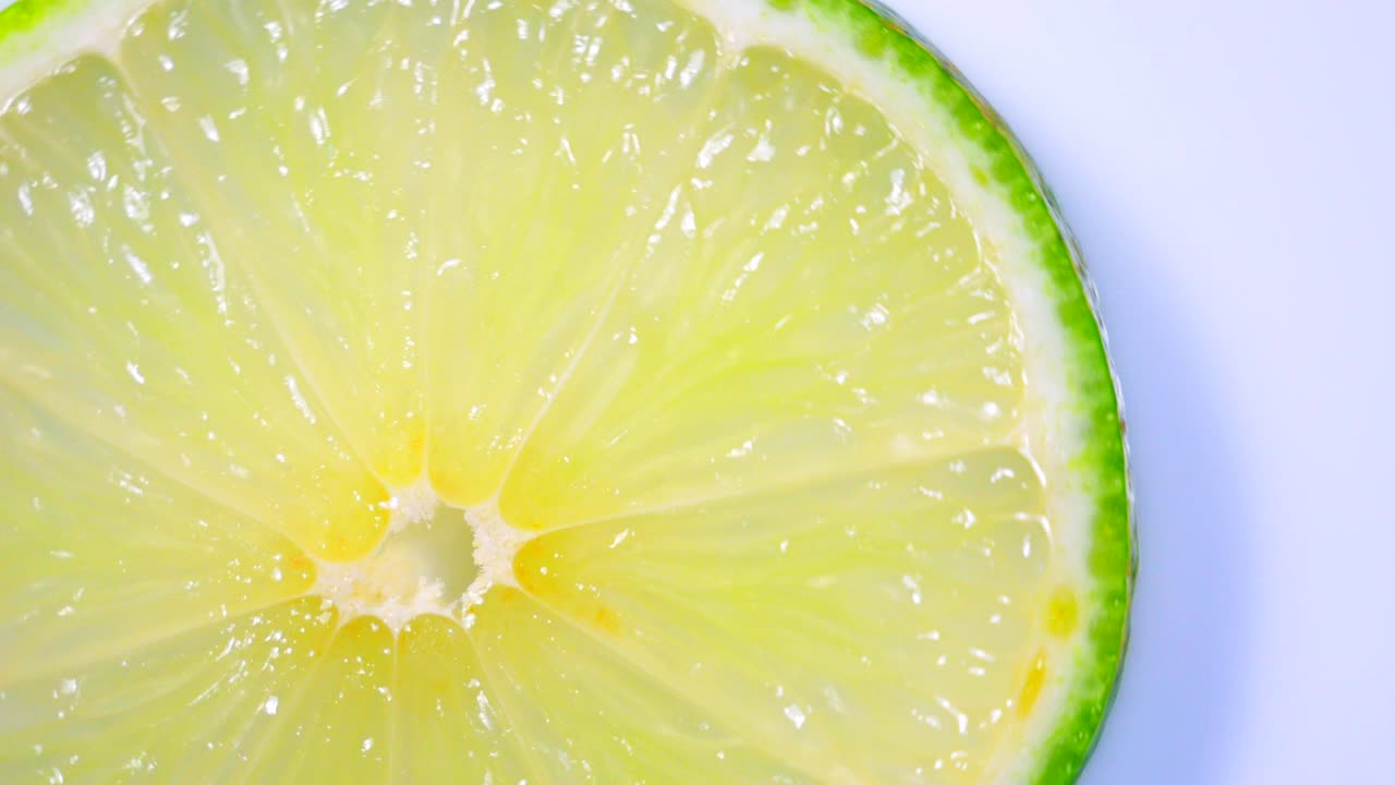 신선한 녹색 레몬 슬라이스는 세부 사항과 함께 스튜디오에서 천천히 회전하고 있습니다.