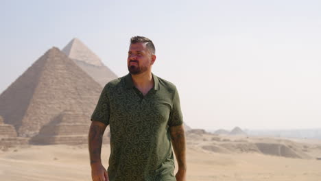 portrait of a man walking on a hot sunny day in the giza plateau of egypt. tracking shot