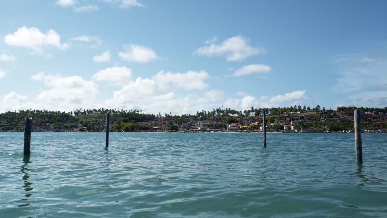 tiro inclinado desde donde el gran río curimataú turquesa tropical se encuentra con el mar desde la playa de restinga frente a la ciudad costera tropical de barra do cunhaú en río grande do norte, brasil