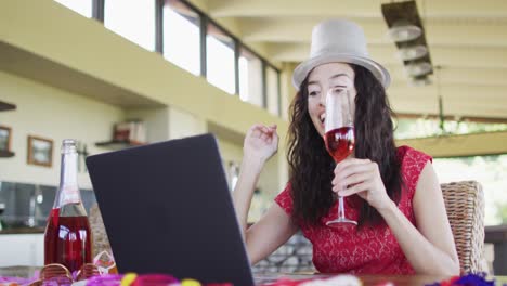 Happy-biracial-woman-making-new-year-video-call,-holding-wine