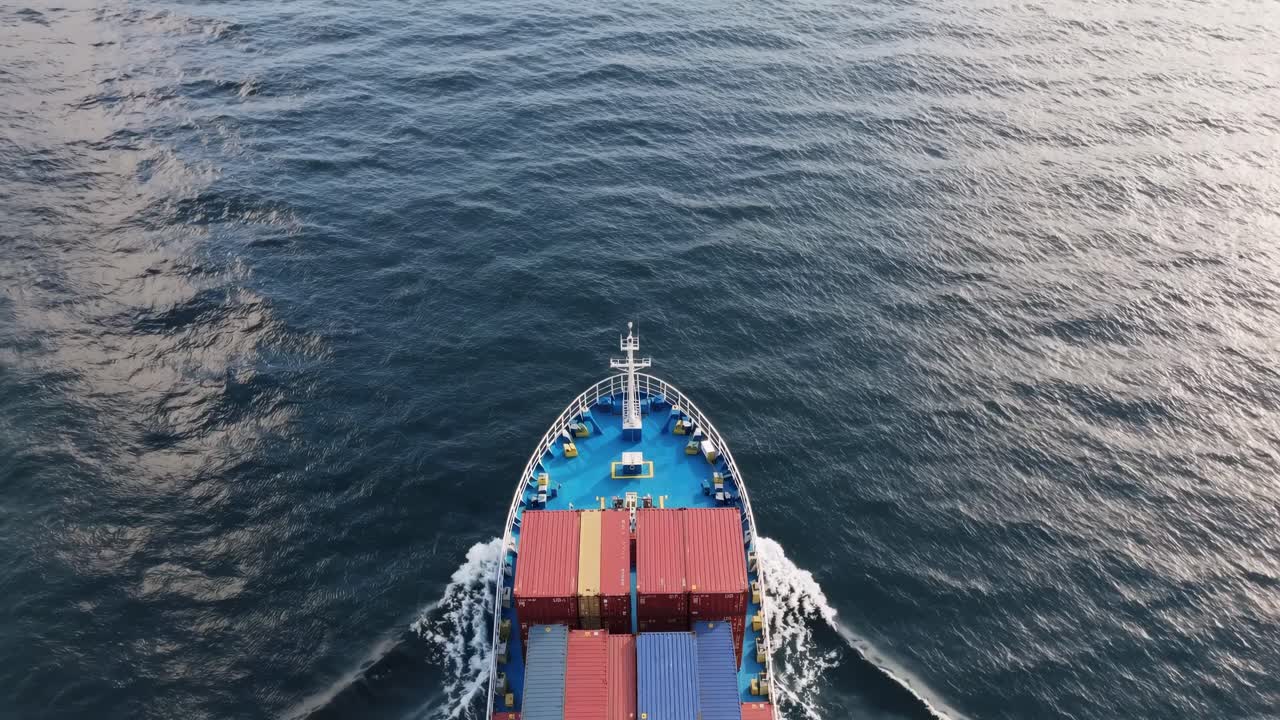 조용한 바다 표면을 가로질러 항해하는 컨테이너 선박, 상공에서 열린 바다 물을 항해하는 동안 독특한 웨이크 패턴을 생성합니다.