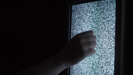 human hand touching old retro television screen with ripples, wavy flowing damaged signal. close-up of broken old-fashioned tv with noise, bad signal reception, cinematography concept