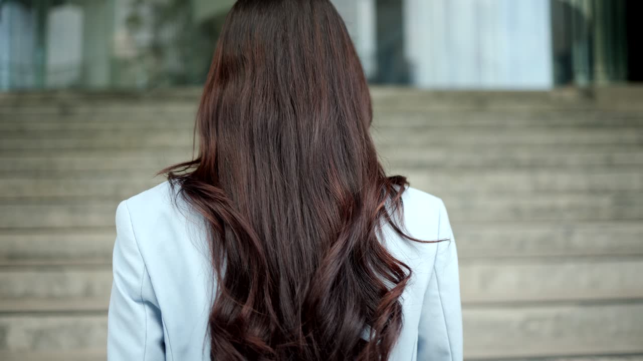 아름다운 사업가 여성이 도심의 건물들 사이의 복도에서 계단을 고 있습니다. 자신감있는 여성들은 도시에서 성공하기 위해 그들의 목표를 향해 걸어갑니다.