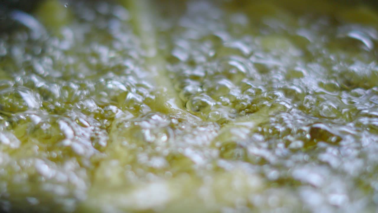 Close Up of Bubbling Hot Oil Cooking French Fries in Deep Fat Fryer in Slow Motion. Unhealthy Fast Food Chips