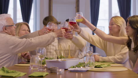 Glückliche-Familie,-Die-Gläser-Klirrt,-Urlaub-Feiert-Und-Zu-Hause-Zusammen-Zu-Abendessen-Genießt