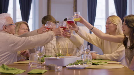 happy family clinking glasses, celebrating holiday and enjoying dinner together at home