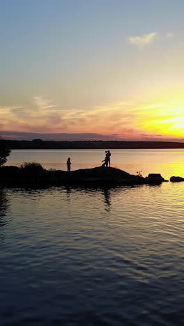 people enjoying the riverside sunset. people relaxing on a river bank, enjoying the riverside sunset vertical video