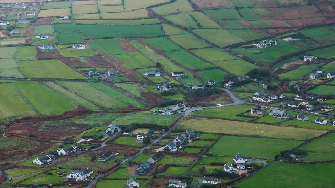 Verdes campos irlandeses rodean casas de piedra en la ladera costera.