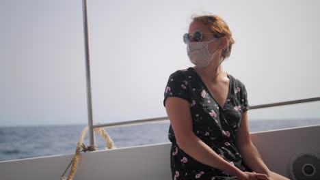 attractive woman wearing face mask and sunglasses while on a boat ride during summer in slow motion