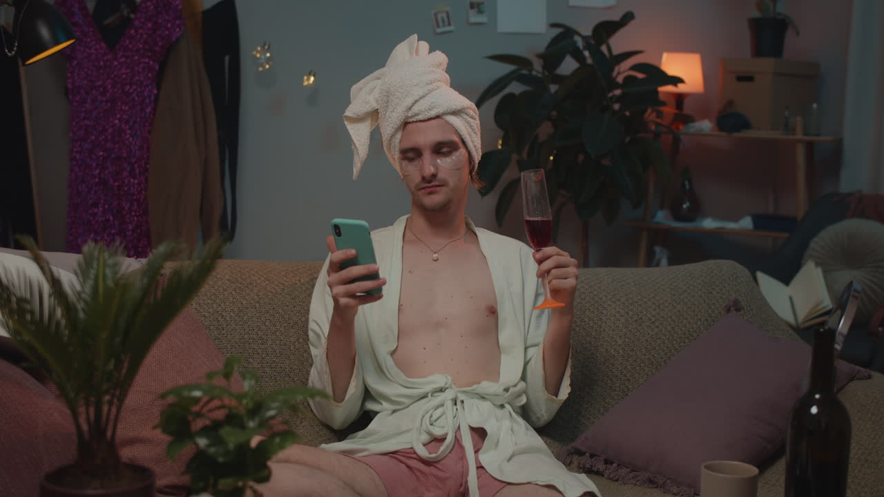 Man relaxing at home with wine and smartphone