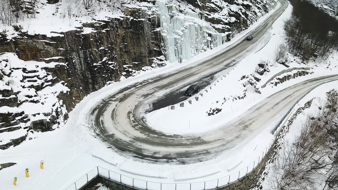 Car Driving In The Road By The Snowy Mountains In Geirangerfjord Norway - aerial shot