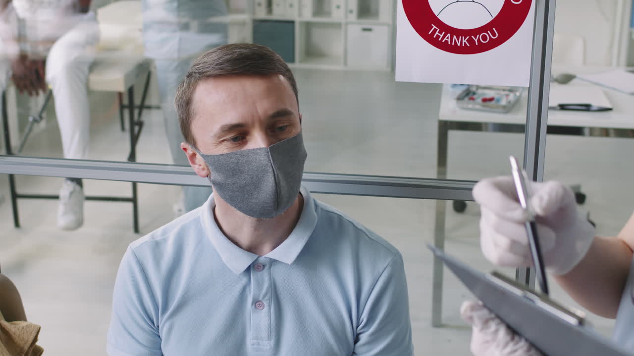 Man In Mask Measuring Temperature At Hospital