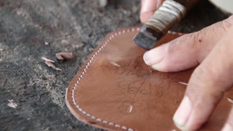 blurry selective focus clip, craftsman when carving leather for decoration, manually in his garage