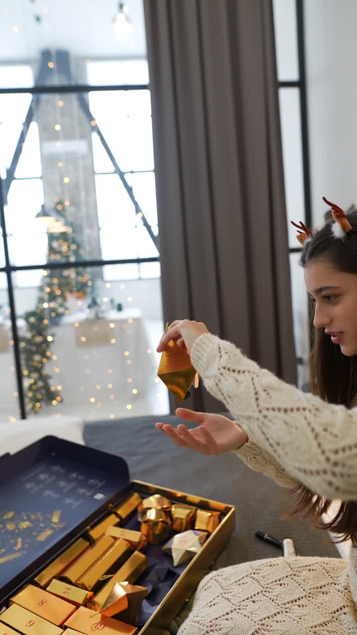 una mujer abriendo el calendario de adviento de navidad y aplicando lápiz labial.