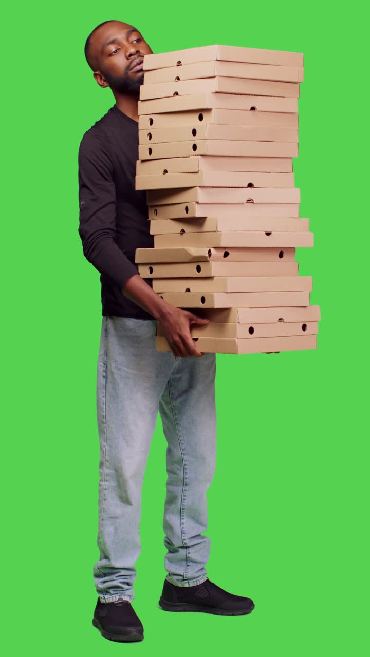 Video verticale: vista laterale di giovane che consegna una grande pila di pizza davanti alla telecamera
