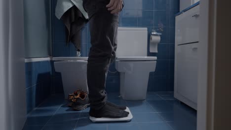 man weighing himself in bathroom