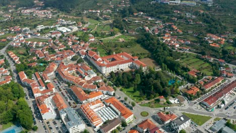 an aerial view capturing 'santa mafalda de arouca monastery' and the surrounding town in aveiro, a district in portugal, taken with a drone