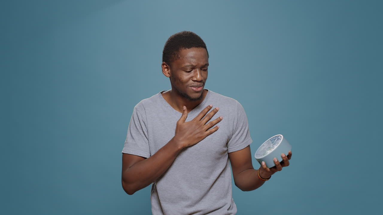 Stressed man checking time on wall clock and running late to work
