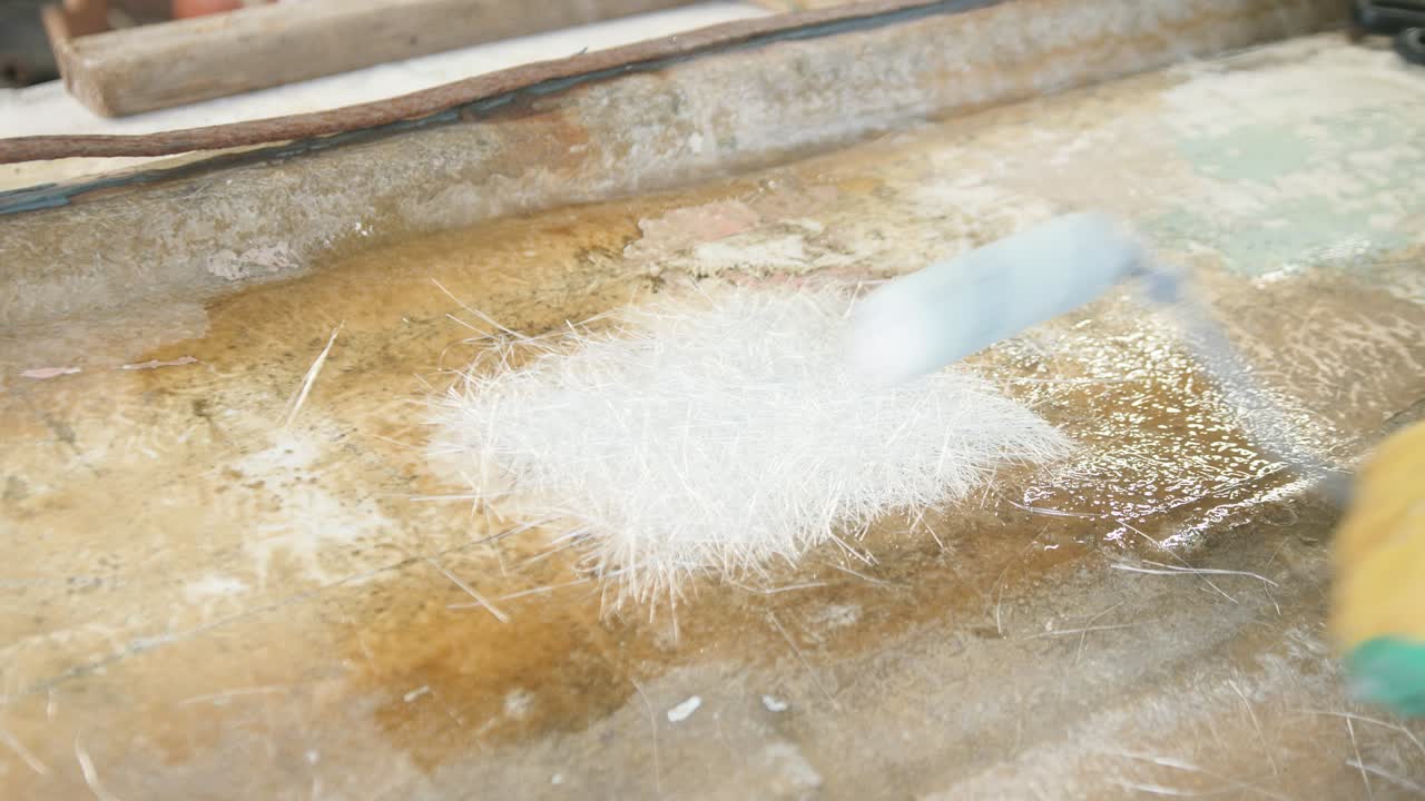 Applying fiberglass mat over hole in boat