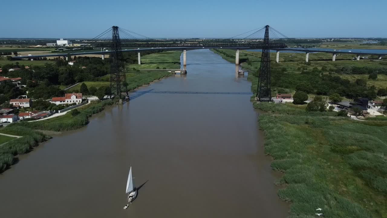 Flying away from the Rochefort bridge revealing a sailboat and birds passing, France